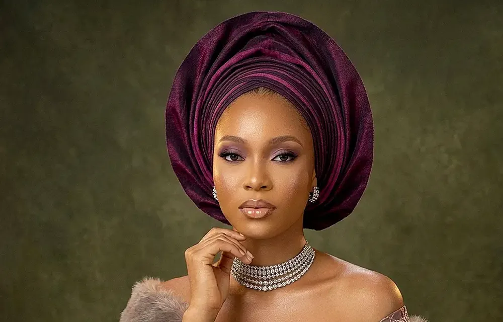 Woman wearing a purple gele headwrap and beaded jewellery for a traditional African wedding celebration